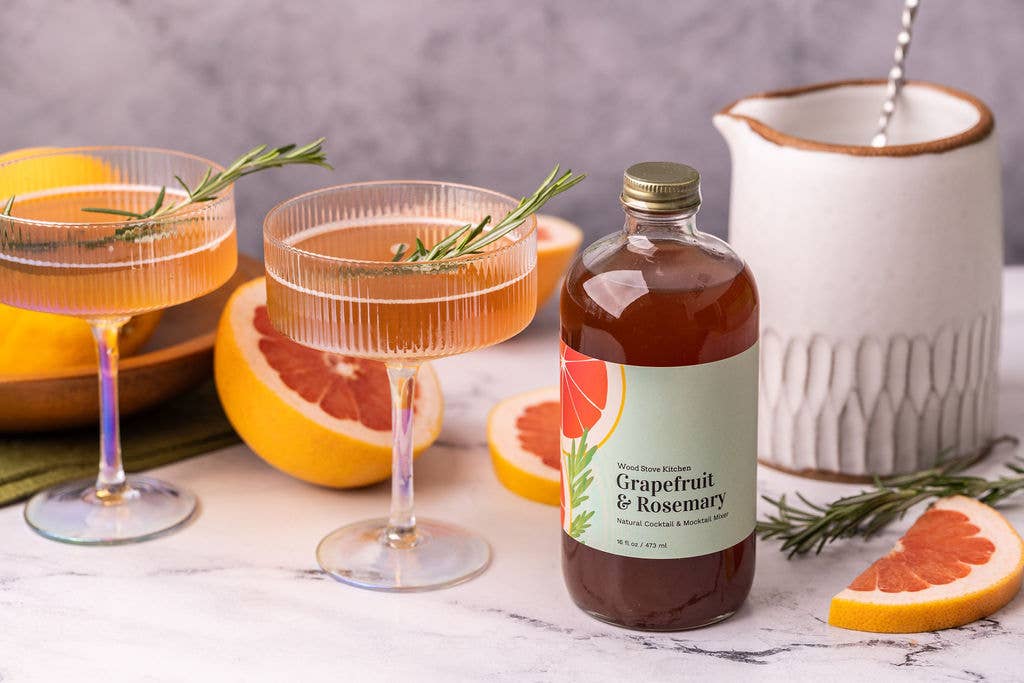 Grapefruit and Rosemary cocktail mixer with cocktails and ingredients on a marble surface